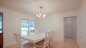 A dining area with a white table and chairs, a ceiling fan, and a view through a window. - Lanai, Golf Views! Extended Sarasota Stay (Sarasota)