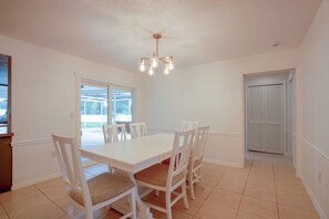 A dining area with a white table and chairs, a ceiling fan, and a view through a window. - Lanai, Golf Views! Extended Sarasota Stay (Sarasota)