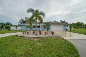 Ein Wohnhaus mit Vorgarten, einer Palme und einer Garage.