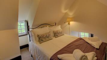 A bedroom with a bed, pillows, a bedside lamp, and a window.