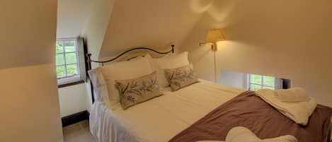 A bedroom with a bed, pillows, a bedside lamp, and a window.