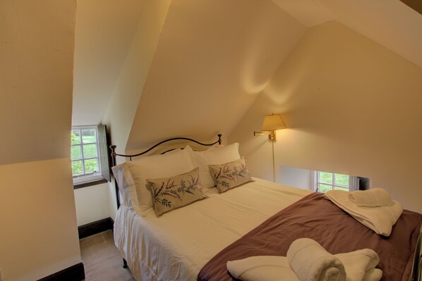 A bedroom with a bed, pillows, a bedside lamp, and a window.