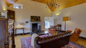 A spacious living room with a fireplace, leather sofa, and a chandelier.