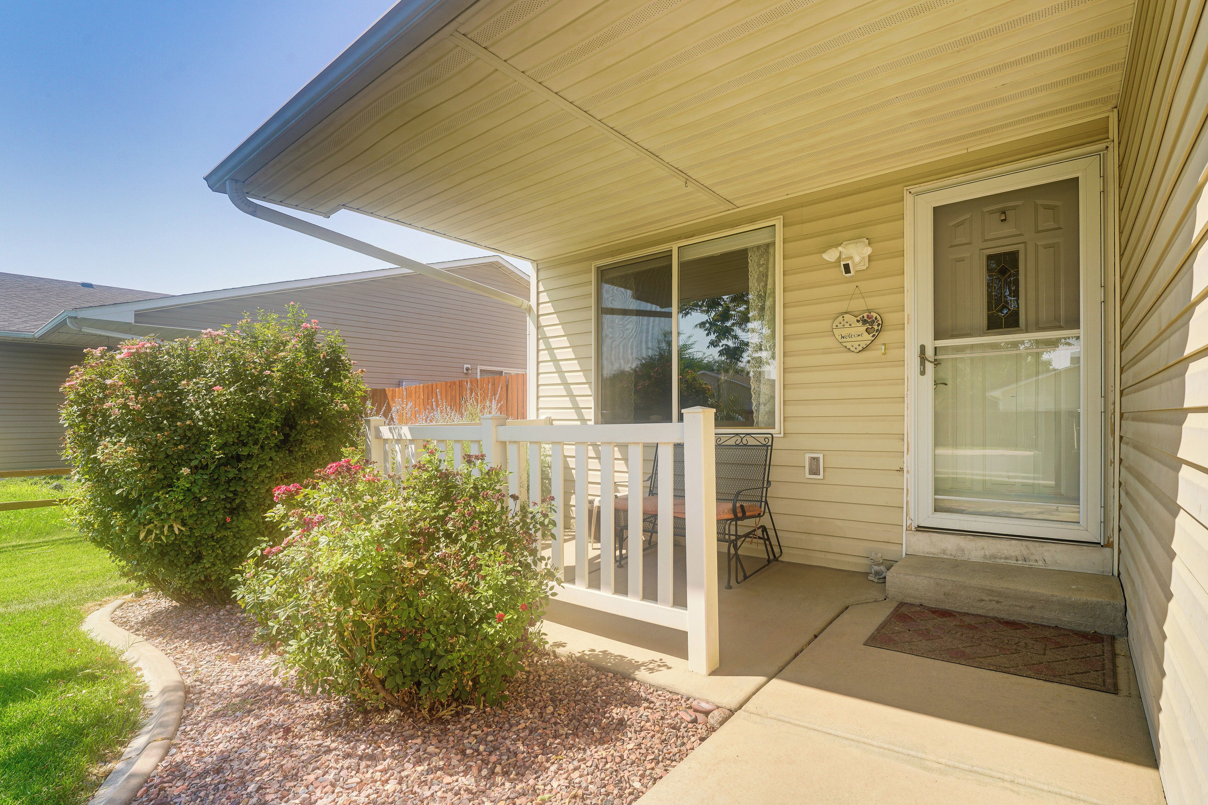 A house with a front porch, a small garden, and a door with a glass panel.