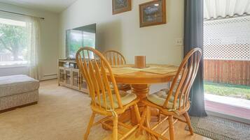 A dining area with a wooden table and chairs, a television, and framed artwork on the wall.