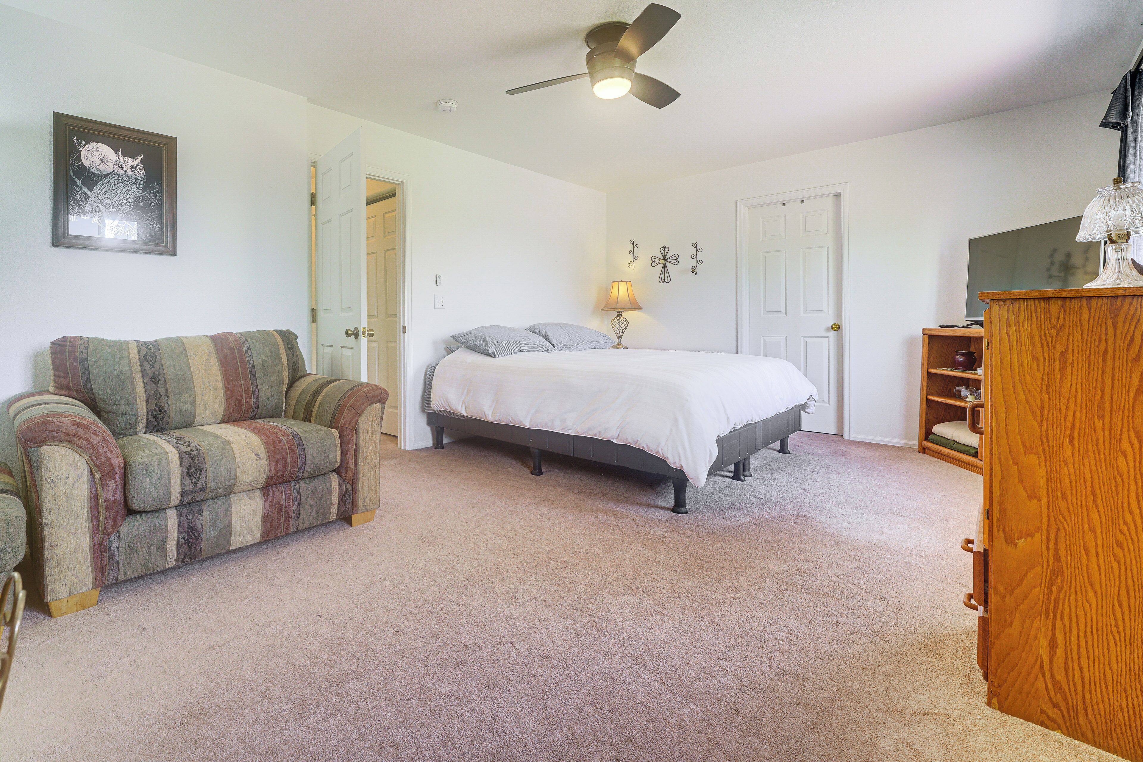 A bedroom with a bed, a chair, a desk, and a ceiling fan.