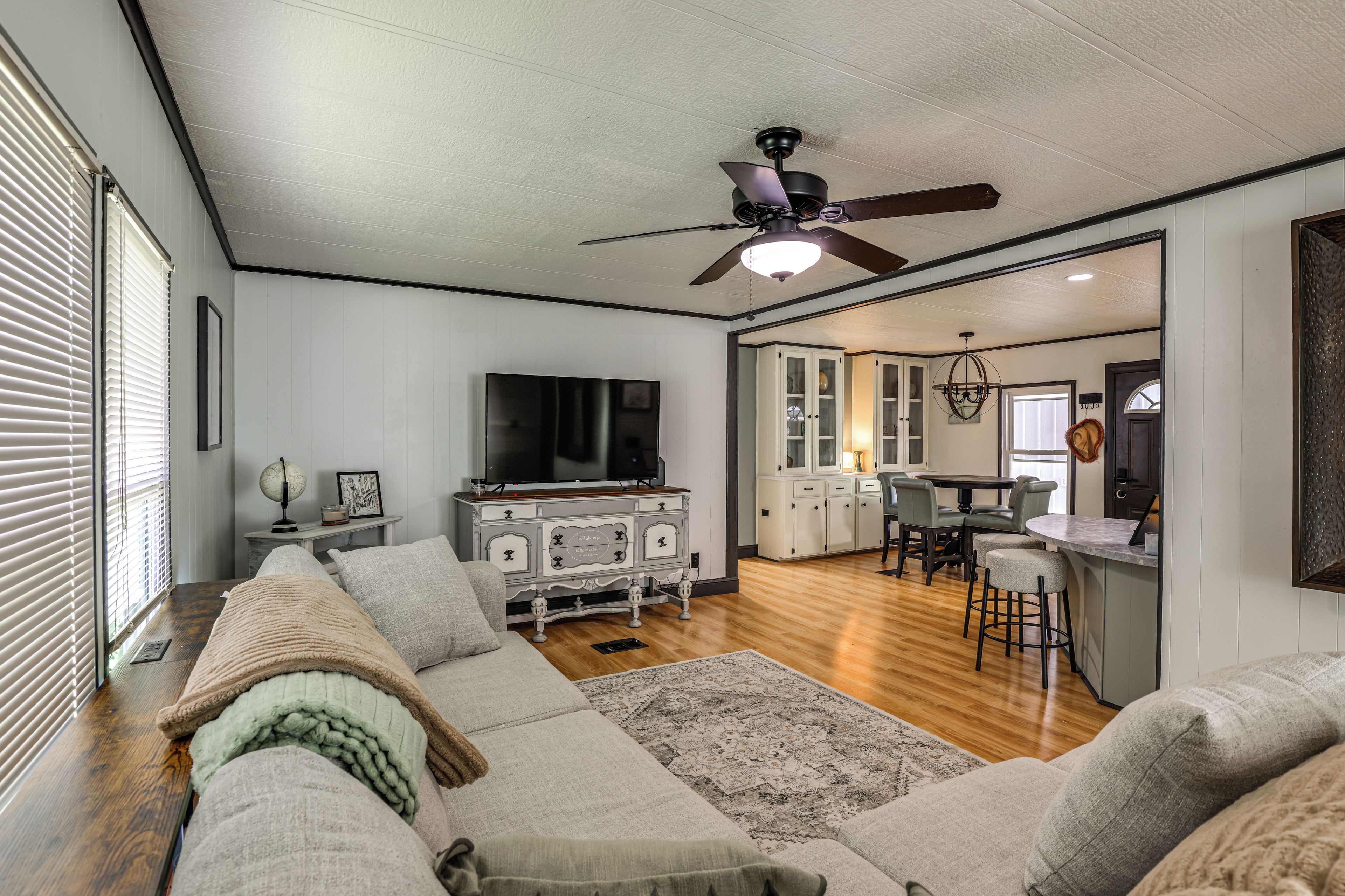 A living room with a sofa, television, and a ceiling fan.