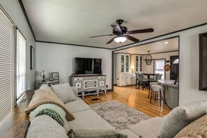 Ein Wohnzimmer mit einer Couch, einem Fernseher und einem Deckenventilator.