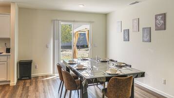 A dining area with a table set for four, chairs, and a view through a glass door to an outdoor space.