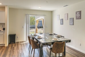 A dining area with a table set for four, chairs, and a view through a glass door to an outdoor space.