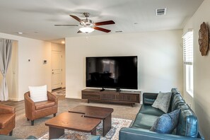 Ein Wohnzimmer mit Flachbildfernseher, Ledersofas, Couchtisch und Deckenventilator.