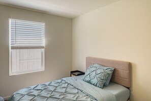 Une chambre à coucher avec un lit, une table de chevet et une fenêtre avec des stores.