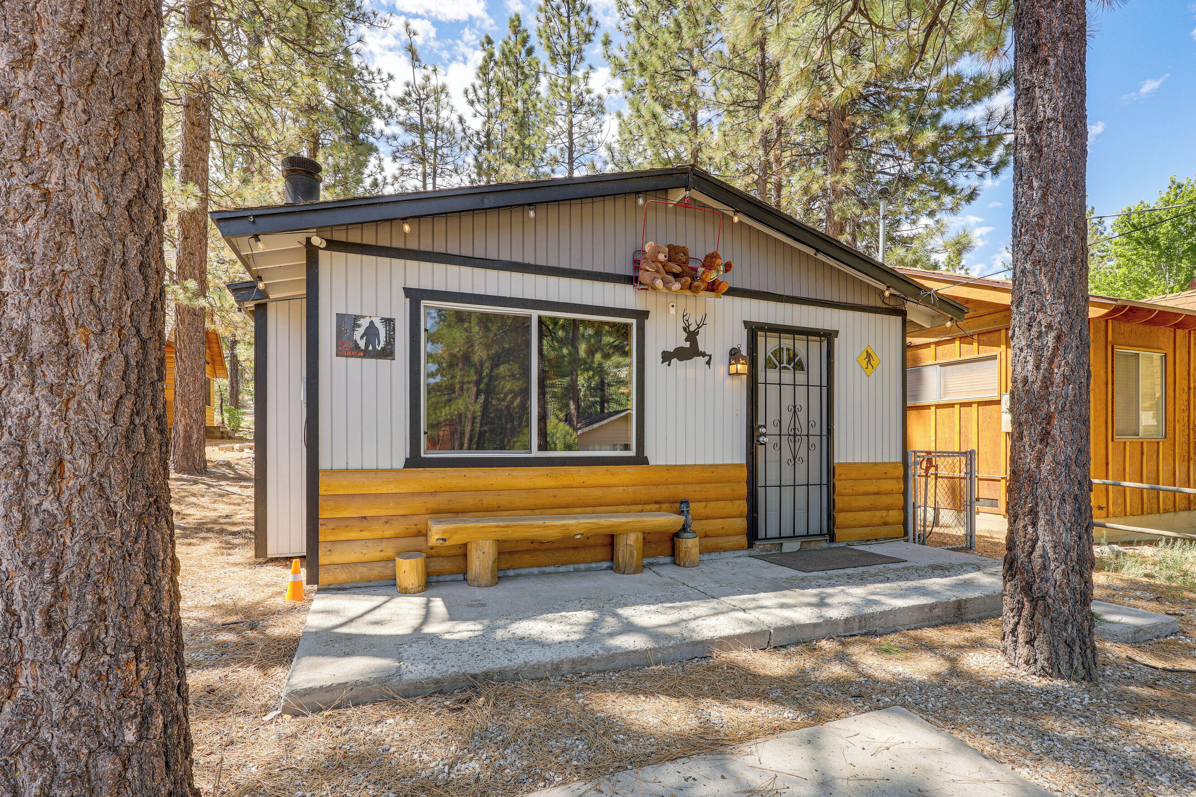 A cabin with a wooden exterior, a bench outside, and a deer silhouette on the wall.