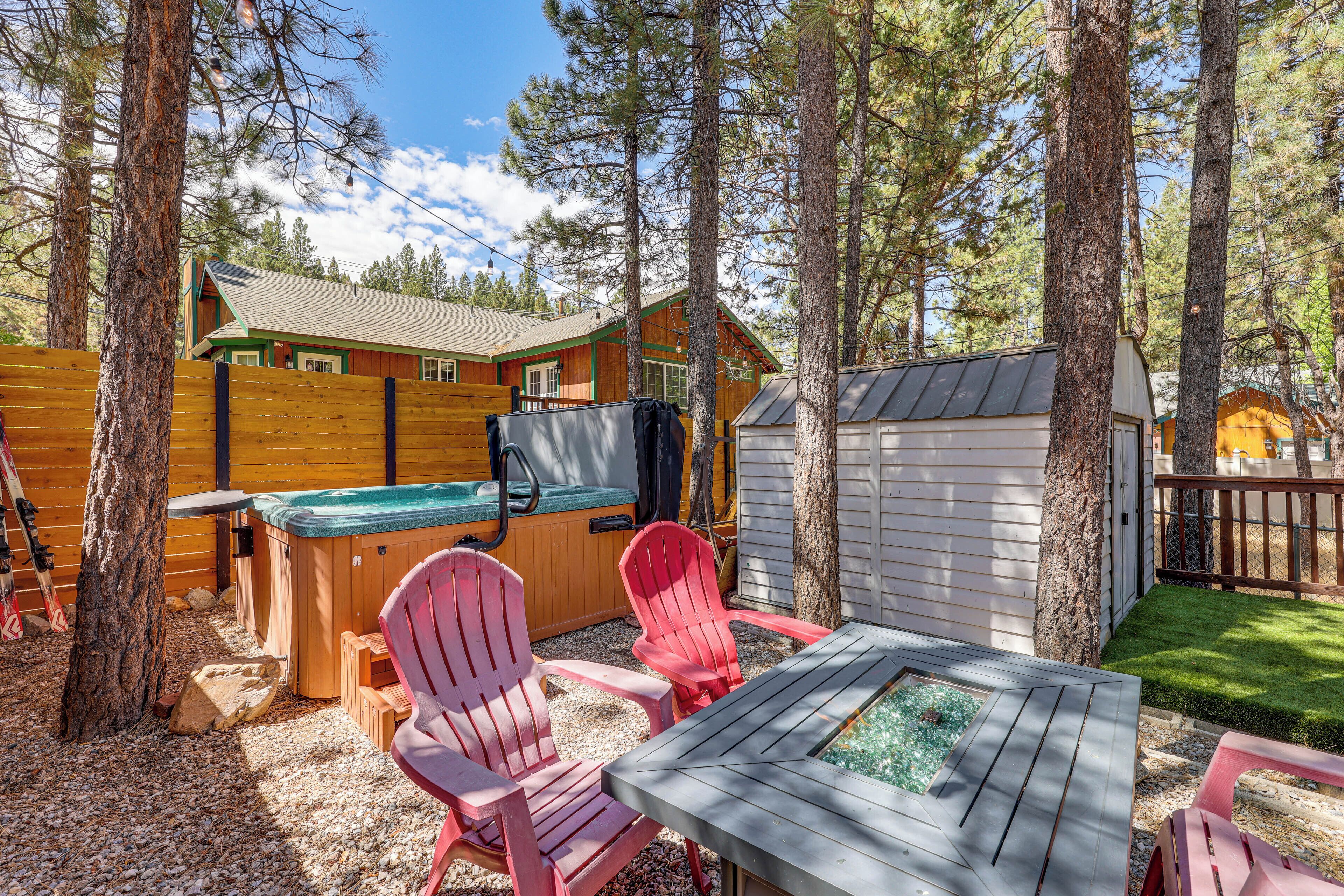 Ein hölzerner Whirlpool, zwei Adirondack-Stühle und eine kleine Terrasse mit einem Tisch mit Glasplatte.