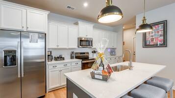 A modern kitchen with white cabinetry, stainless steel appliances, and a central island with seating.