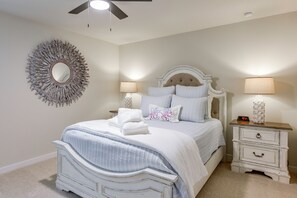 Ein Schlafzimmer mit einem Bett, zwei Nachttischen, einem Wandspiegel und einem Deckenventilator.