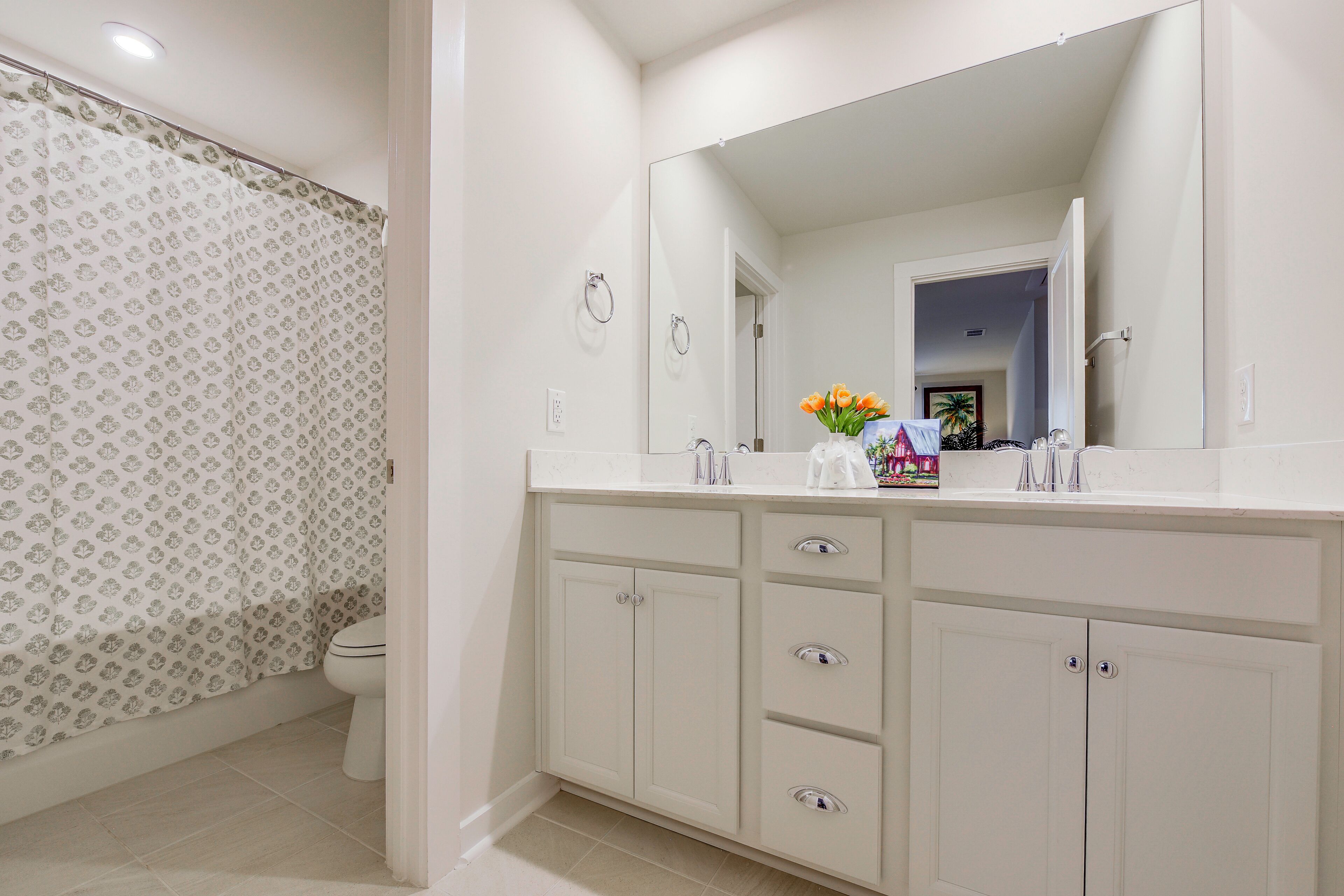 A bathroom with a white vanity, a mirror, and a toilet.