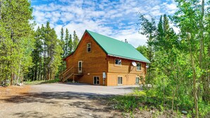 A two-story log cabin with a green roof, surrounded by a forest. - Pool Table & Peaceful Porch: Fairplay Retreat (Fairplay)