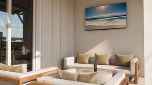 Un salon moderne avec un ensemble de canapés, une table basse et un téléviseur fixé au mur qui diffuse une scène de plage.