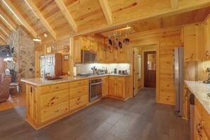 Eine geräumige Küche mit Holzschränken, einer Akzentwand aus Stein und einem Kamin aus Stein.