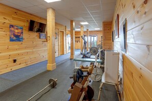 Une salle de sport avec des murs en bois, un téléviseur et du matériel d’exercice.