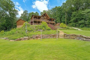 A large wooden cabin with a balcony, surrounded by lush greenery and a stone wall. - Mountain Top Lodge With Amazing Vista (Jasper)