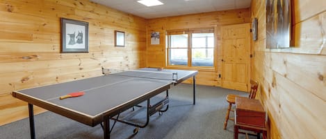 A ping pong table in a room with wooden walls and a window.