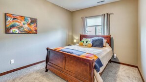 A bedroom with a wooden bed, a colorful abstract painting, and a window with curtains. - Private Yard w/ Patio! Rapid City Escape (Rapid City)