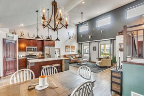 A spacious kitchen with a central island, a dining area with a wooden table, and a living room with a large window. - Private Yard w/ Patio! Rapid City Escape (Rapid City)