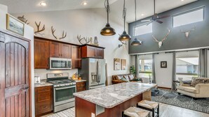 A spacious kitchen with a large island, stainless steel appliances, and a dining area with a sofa and bar stools. - Private Yard w/ Patio! Rapid City Escape (Rapid City)