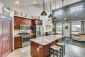 A spacious kitchen with a large island, stainless steel appliances, and a dining area with a sofa and bar stools.