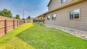 A residential property with a well-maintained lawn, a wooden fence, and a house with multiple windows and a covered porch. - Private Yard w/ Patio! Rapid City Escape (Rapid City)
