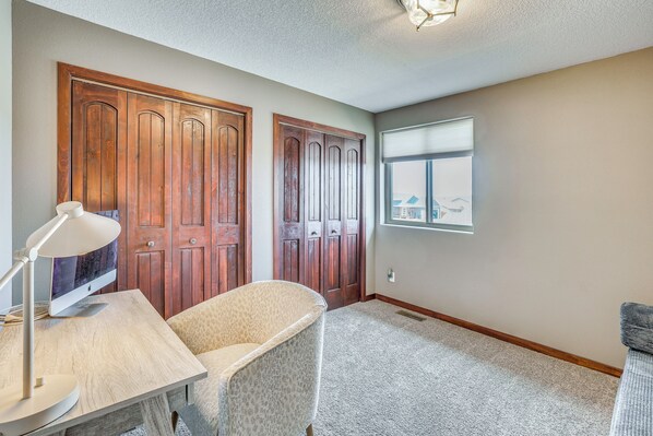 A room with a desk, a chair, a lamp, and a window with blinds. - Private Yard w/ Patio! Rapid City Escape (Rapid City)