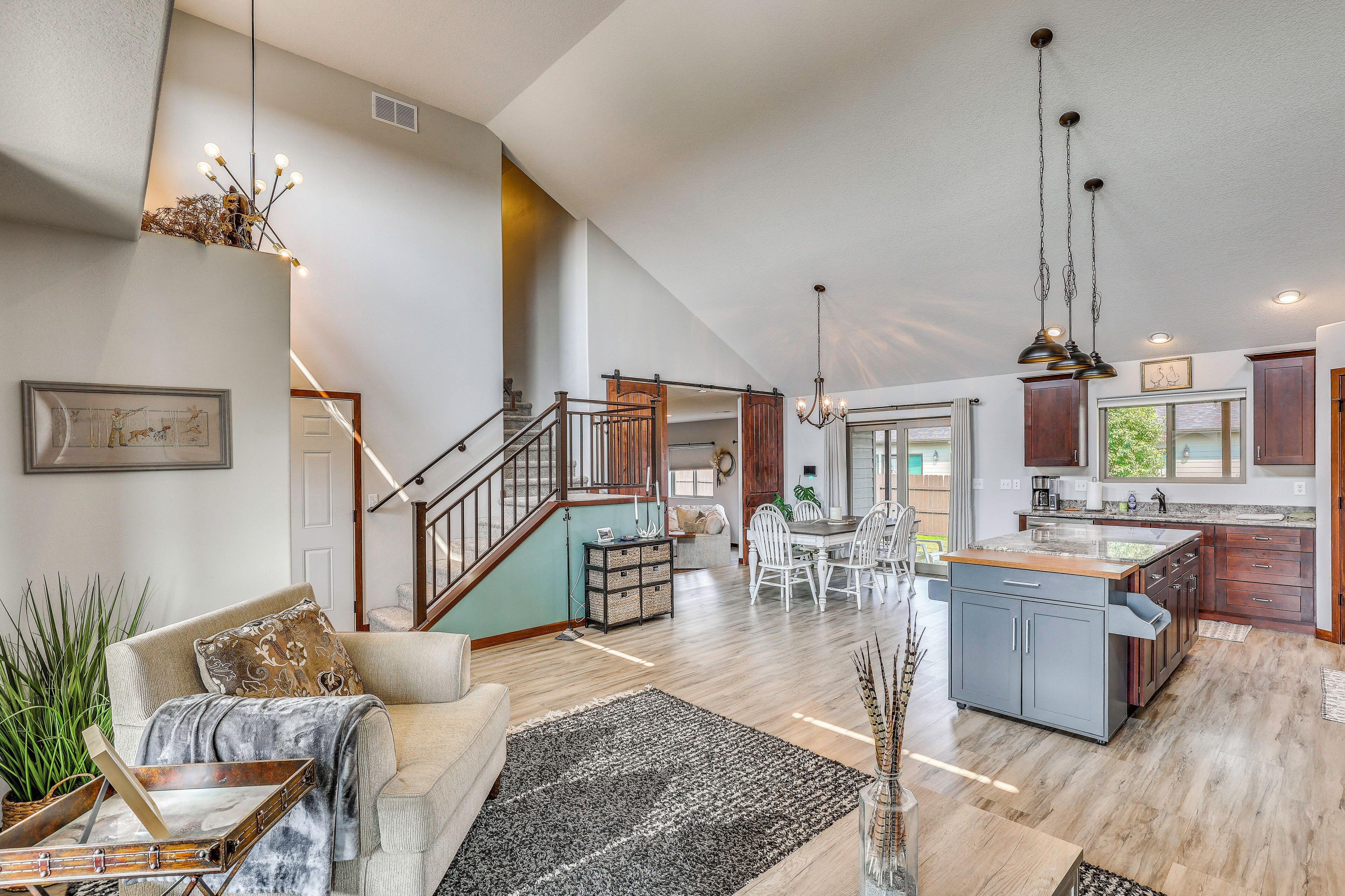 A spacious living area with a staircase, a dining table, and a kitchen area with a large island.