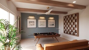Ein Zimmer mit einer Tischfußballplatte, einem Deckenventilator, gerahmten Bildern und einem Schachbrett.