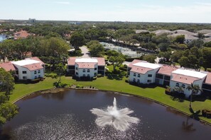 A large building complex with multiple white structures and red roofs, surrounded by green lawns and a central pond with a fountain. - < 1 Mi to Beach! Top-floor Naples Retreat w/ Pool (Naples)