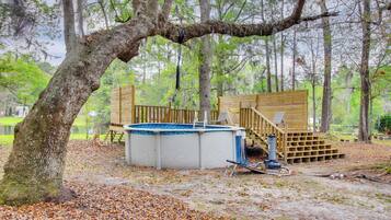 A wooden deck with a hot tub, surrounded by trees and a natural setting.