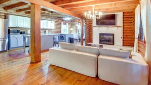 A log cabin interior with a living area, kitchen, and fireplace. - Pool & Fishing at Lakefront Midway Retreat (Midway)