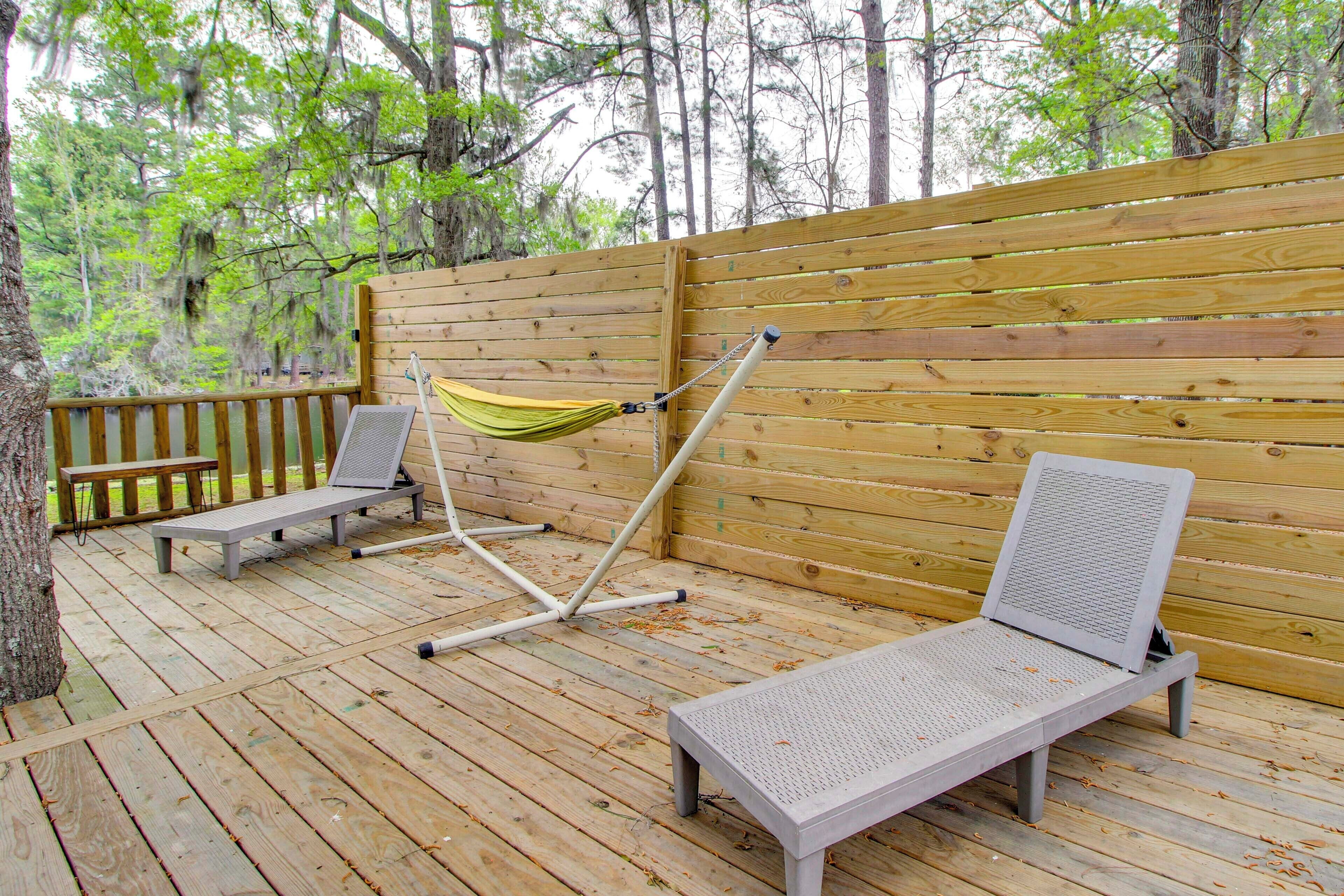Une terrasse en bois avec deux chaises longues, un hamac et un banc.