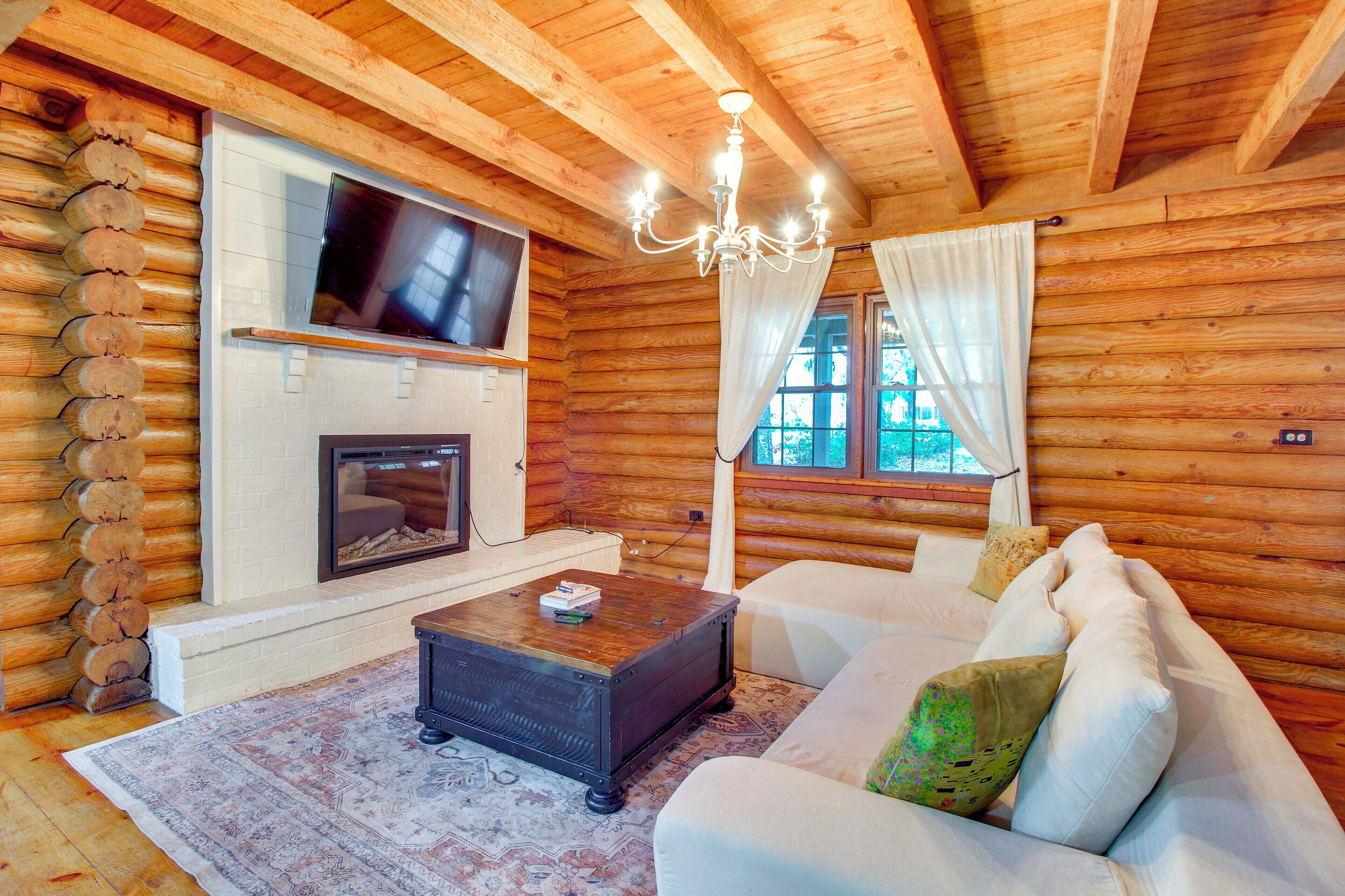 A log cabin interior with a fireplace, television, and a sofa.