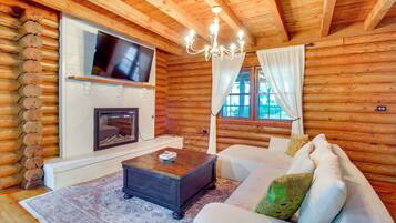 A log cabin interior with a fireplace, television, and a sofa.