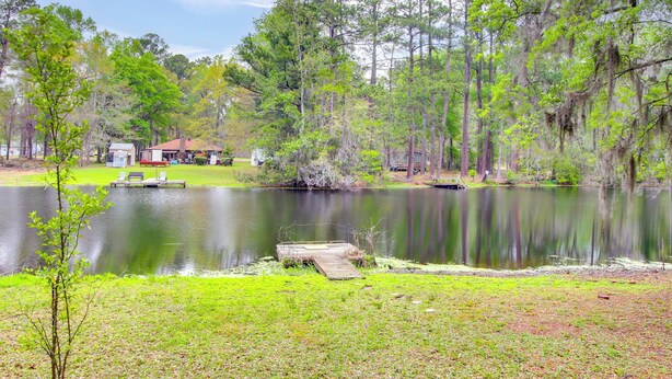 A lakeside property with a dock, a small house, and a boat. - Pool & Fishing at Lakefront Midway Retreat (Midway)