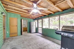 Une cuisine équipée d’un ventilateur de plafond, d’un réfrigérateur, d’un barbecue et de grandes fenêtres.