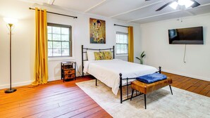 A bedroom with a bed, a bench, a floor lamp, a painting, and a television. - Pool & Fishing at Lakefront Midway Retreat (Midway)