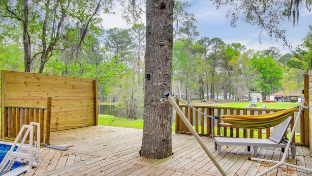 A wooden deck with a hammock, a pool, and a view of a lake surrounded by trees. - Pool & Fishing at Lakefront Midway Retreat (Midway)