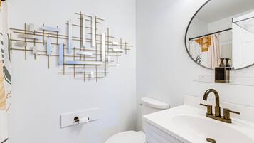 A bathroom with a modern design, featuring a toilet, a sink with a gold faucet, and a wall-mounted towel rack.