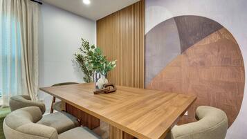 A modern meeting room with a wooden table, six chairs, a vase with greenery, and a large abstract wall mural.