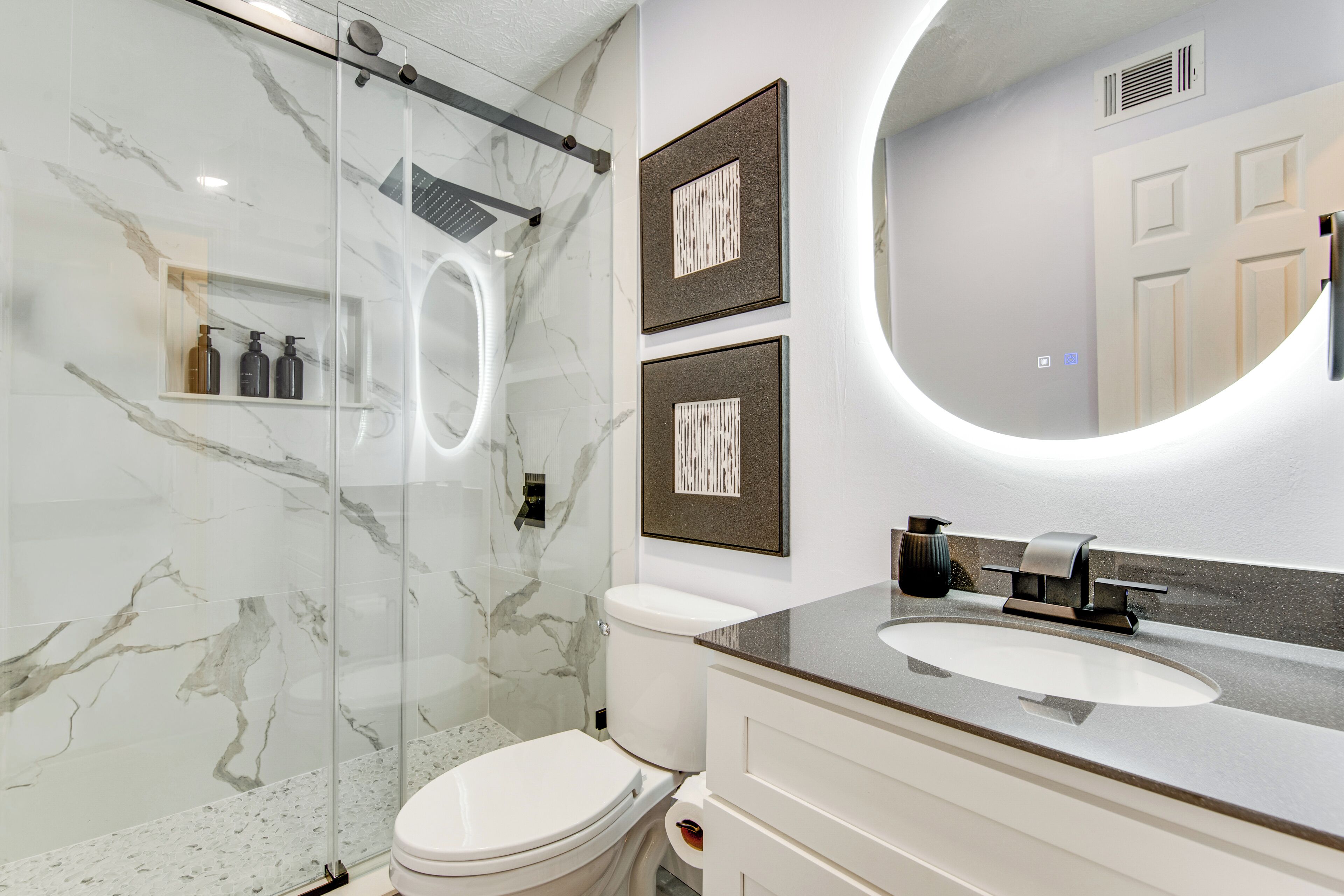 A modern bathroom with a glass shower enclosure, a white toilet, and a vanity with a sink.