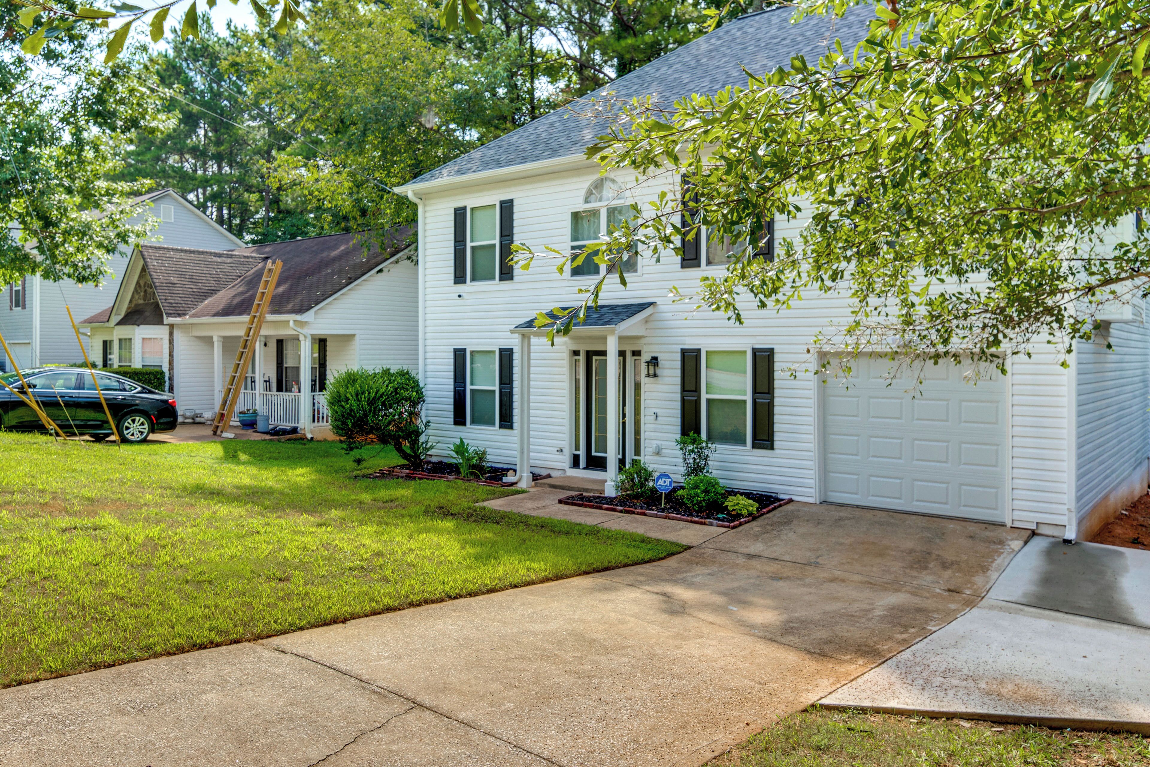 A two-story residential house with a front porch, a garage, and a well-maintained lawn.