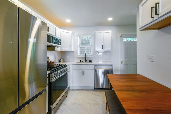 A compact kitchen with a stainless steel refrigerator, a stove, and a dishwasher.